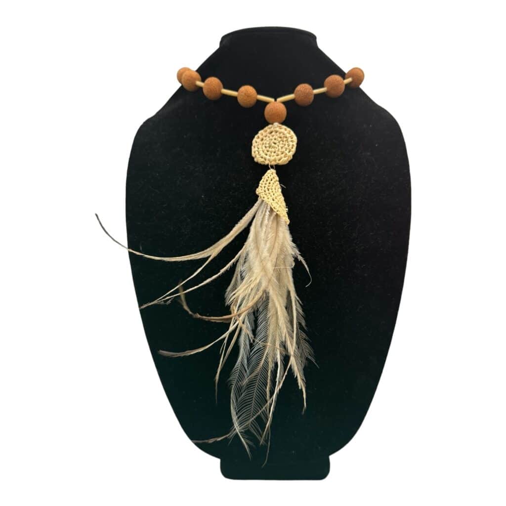 Discover the elegance of "Golden Dream," a handwoven necklace from Debbie Wood's "The NAIDOC Collection." Featuring raffia, golden emu feathers, echidna quills, rare hand-carved sandalwood beads, and quandong seeds, this piece is a serene celebration of Aboriginal craftsmanship.