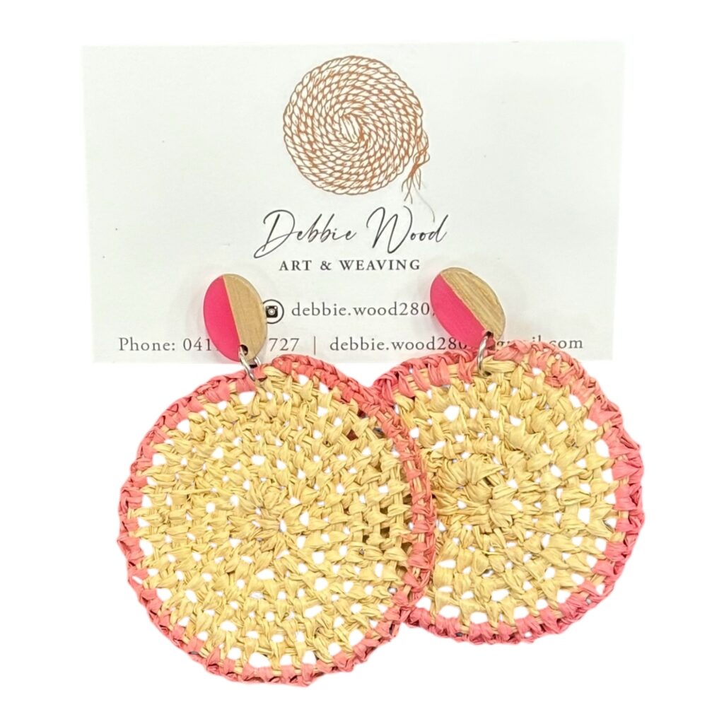 Sunset Glow handwoven earrings by Gomeroi artist Debbie Wood. Natural raffia with a pink rim captures the warmth of a sunset in a stylish design.